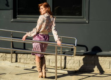 Güneşli bahar aylarında binanın arka planında uzun saçlı, şık ve alımlı güzel bir kadının parlak havasında çekilmiş bir fotoğraf..