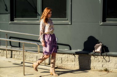 Güneşli bahar aylarında, binanın arka planında uzun saçlı, şık, alımlı, güzel bir kadının parlak havada çekilmiş uzun bir fotoğrafı..