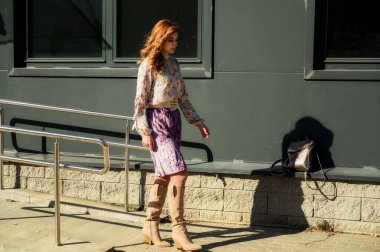 Güneşli bahar aylarında, binanın arka planında uzun saçlı, şık, alımlı, güzel bir kadının parlak havada çekilmiş uzun bir fotoğrafı..