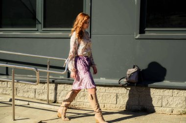 Şık, alımlı, güzel bir kadının tam boy fotoğrafı. Arka planda uzun saçları olan. Baharda güneşin altında, binanın merdivenlerinde..