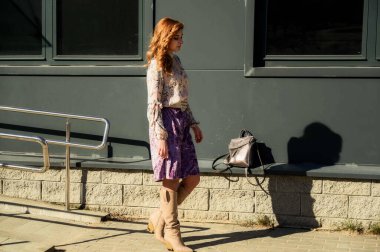 Şık, alımlı, güzel bir kadının tam boy fotoğrafı. Arka planda uzun saçları olan. Baharda güneşin altında, binanın merdivenlerinde..