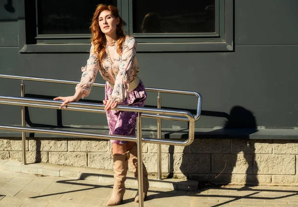 Güneşli bahar aylarında binanın arka planında uzun saçlı, şık ve alımlı güzel bir kadının parlak havasında çekilmiş bir fotoğraf..