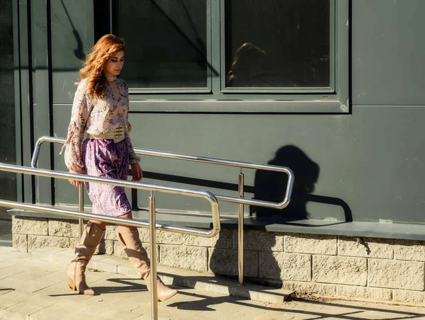 Güneşli bahar aylarında, binanın arka planında uzun saçlı, şık, alımlı, güzel bir kadının parlak havada çekilmiş uzun bir fotoğrafı..