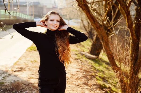 一个长头发的时髦的年轻女子的画像 在公园的路况树的背景上挂着一个微笑 图为春季室外天气晴朗时的照片 — 图库照片