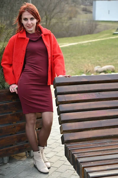 Фото Рыжеволосой Девушки Красной Куртке Бордовом Платье Отдыхающей Открытом Воздухе — стоковое фото