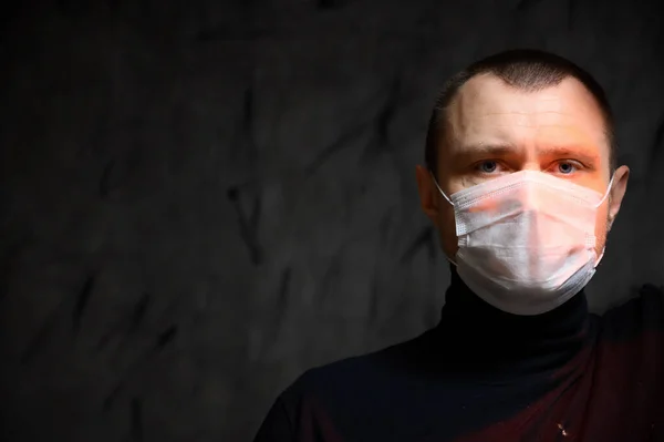 Photo Caucasian man in a medical mask with a red light on a black background