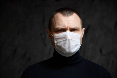 Coronavirus koruma konsepti. Siyah arka planda maskeli bir adamın fotoğrafı. Duyguları olan.