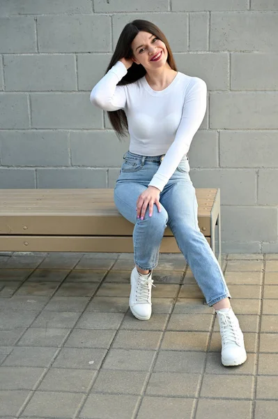 Foto Uma Menina Morena Caucasiana Uma Blusa Branca Jeans Azuis — Fotografia de Stock