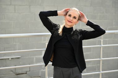 Güneşli bir günde, açık havada gülümseyen güzel beyaz bir kadının fotoğrafı. Gülümseyen ve zevk veren modaya uygun bir model..