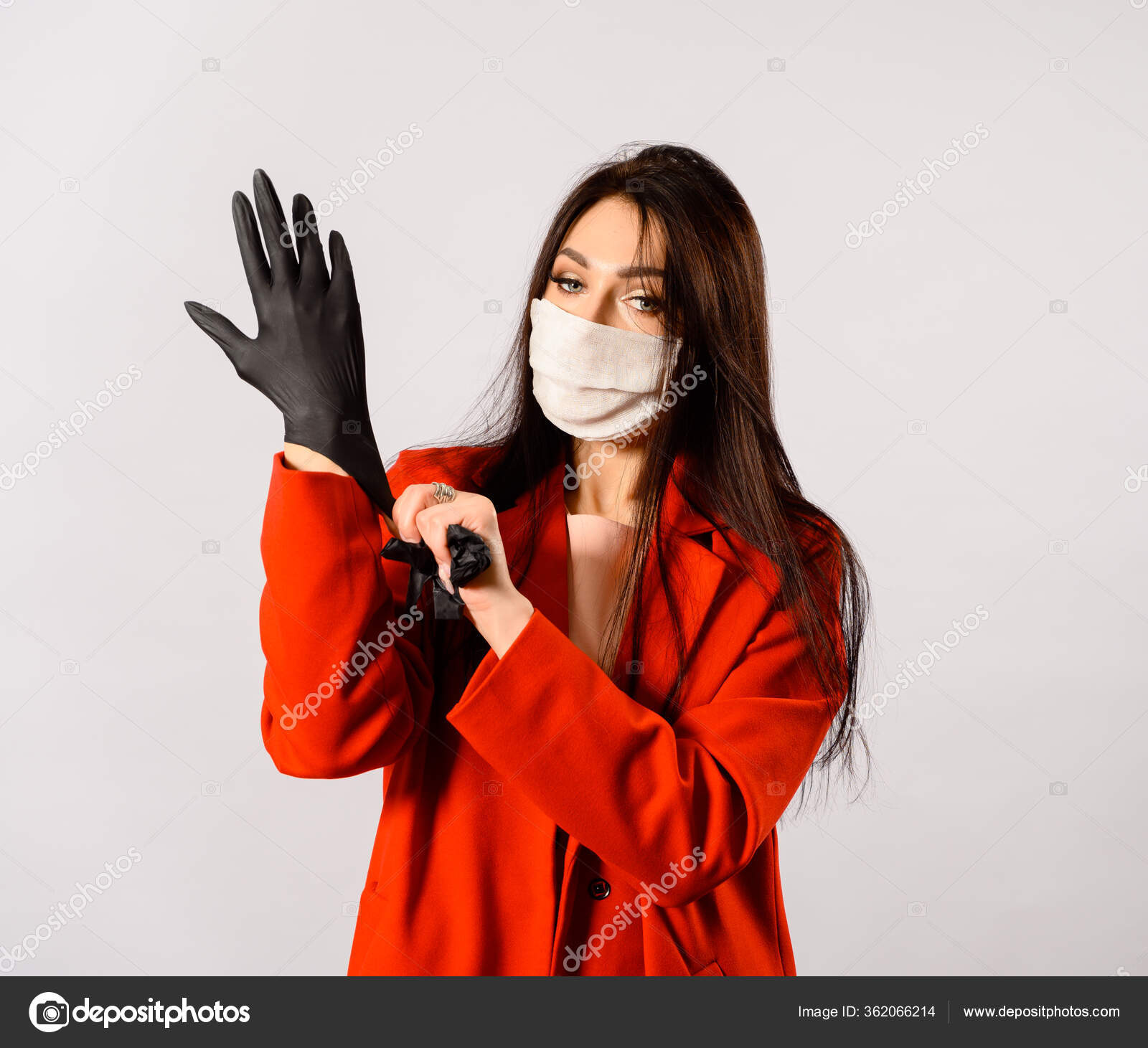 一个年轻漂亮的白种人黑发女子的画像她穿着红色外套戴着医疗保护面具戴着白色背景的黑色手套妆容华丽 图库照片 C Govorkov Photo