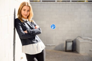 Şehrin güneşli bir gününde, dışarıda ceketli beyaz bir kızın portresi bir binanın arka planında..