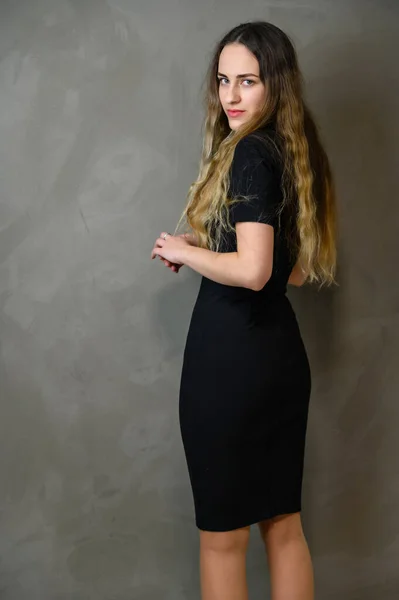 Gri Arka Planda Siyah Bir Elbise Giymiş Uzun Kıvırcık Saçlı — Stok fotoğraf