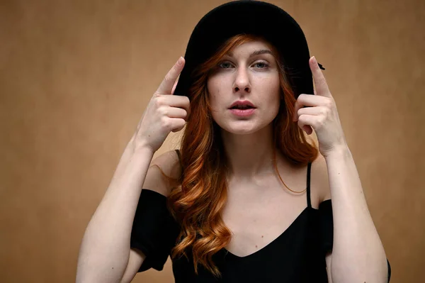 Siyah Şapkalı Bir Model Bej Arka Planda Uzun Kızıl Saçlı — Stok fotoğraf