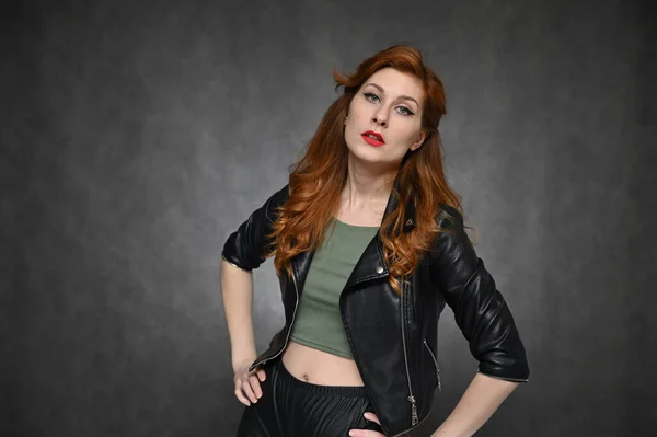 黒のジャケットと緑のTシャツに赤い髪の若い女性の水平線の肖像画 モデルとともに優れたメイクポージング上の灰色の背景でザ スタジオ — ストック写真