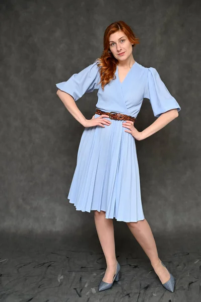全长肖像一个年轻漂亮的红头发女人在灰色背景的蓝色连衣裙 模型展示了不同的姿势 — 图库照片