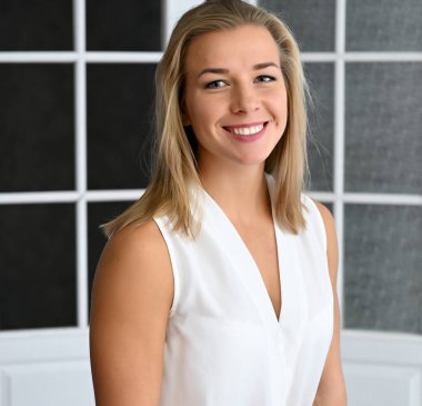 Ofiste beyaz bluzlu, siyah bir arka planda beyaz bir sarışın kızın yakın plan portresi.