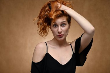 Makyajsız poz ver. Bej arkaplanda uzun kızıl saçlı güzel bir kadının yakın plan portresi..