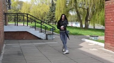 Mükemmel makyajlı esmer bir kızın video portresi. Şemsiyeyle poz veriyor. Şehir parkında gülümsüyor.