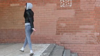 Harika makyajlı esmer kız merdivenlerden çıkıp gülümseyerek caddeye çıkıyor.