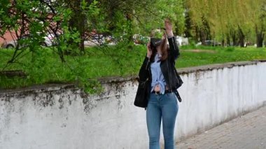 Tıbbi maskeli genç bir kızın video portresi. Telefonda konuşuyor. Şehirde, parkta, sokakta.