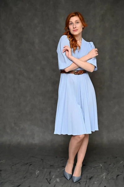 Ολόσωμο πορτραίτο μιας νεαρής όμορφης κοκκινομάλλας με μπλε φόρεμα σε γκρι φόντο. Μοντέλο επιδεικνύει στέκεται διαφορετικές στάσεις. — Φωτογραφία Αρχείου