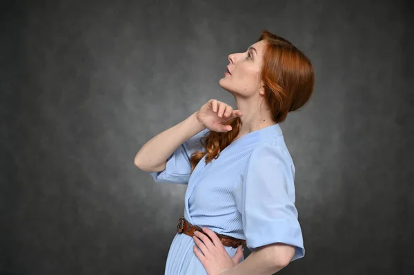 Retrato de uma jovem atriz ruiva bonita em um vestido azul em um fundo cinza. O modelo mostra emoções diferentes . — Fotografia de Stock