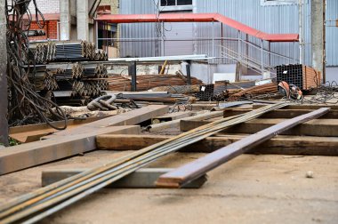 Açık havada, siyah metal yığınları içinde yatan palet yığınları.