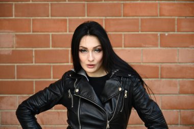 Bina duvarına karşı poz veren bir model. Bahar havasında yakın plan bir portre, açık havada siyah ceketli esmer kız..