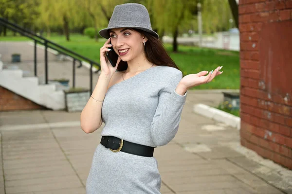 모자를 여자가 전화로 이야기하는 야외에 공원에서 포즈를 취하는 — 스톡 사진