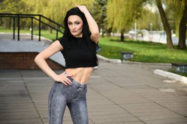 Model, güzel havada bir şehir parkının arka planına karşı duruyor. Bahar havasında portre Kafkas esmer kız ince bir figürle zevkle poz veriyor..