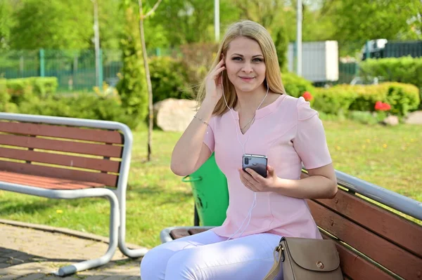 야외에서 스마트폰으로 말하고 귀여운 코카서스 소녀의 공원의 날씨에 벤치에 아름다운 — 스톡 사진