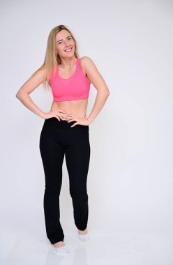 İnce, beyaz bir model çeşitli pozlarda gülümseyerek poz veriyor. Güzel bir fitness kızı portresi. Spor üniformalı, beyaz bir arka planı var..