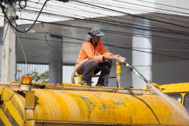 Adam yol merkezi bir ağaçta tank kamyon üzerinde sulama