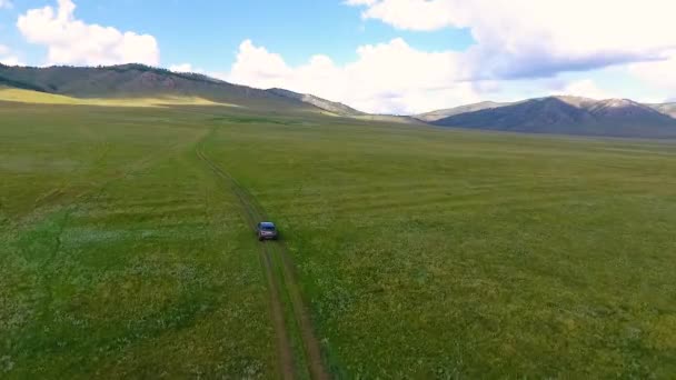 Uma vista do ar para prados verdes, colinas à distância e um carro andando off-road na República de Khakassia. Rússia — Vídeo de Stock