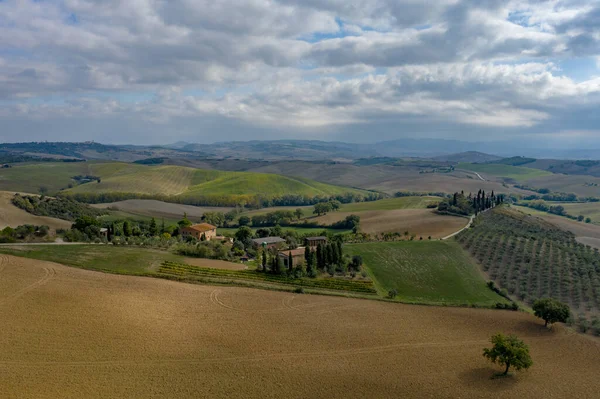 Vista aérea de uma paisagem rural na Toscana. Fazenda rural, vinhas, ciprestes, luz solar e nuvens. Itália, Europa . — Fotografia de Stock