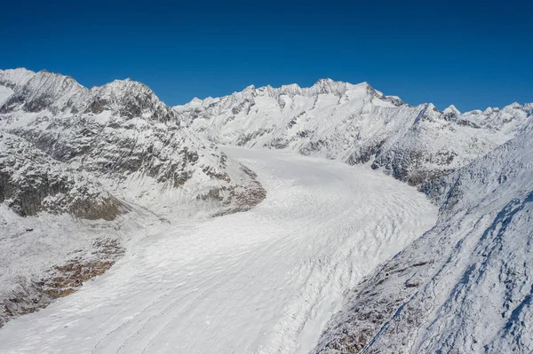 Aerial view of a forest covered with fresh snow and clouds in the Aletsch Arena area. Switzerland in the fall