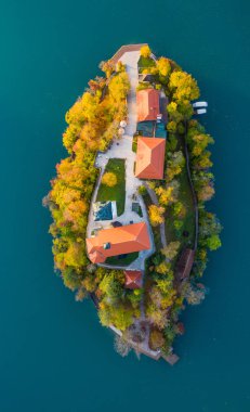 Renkli ormanın havadan görünüşü ve Bled Gölü küçük bir adanın kilisesi. Slovenya 'da sonbaharda gün doğumu.