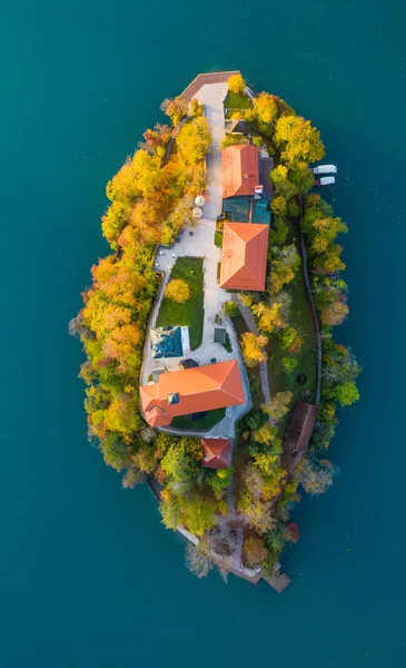 Flygfoto över den färgglada skogen och sjön Bled med en liten ö med en kyrka. Soluppgång i Slovenien på hösten. — Stockfoto