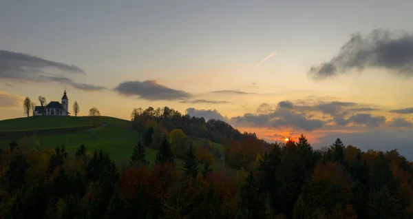 Vista aérea das colinas, floresta colorida e a igreja Sv Sobota. Eslovénia pôr do sol no outono — Fotografia de Stock