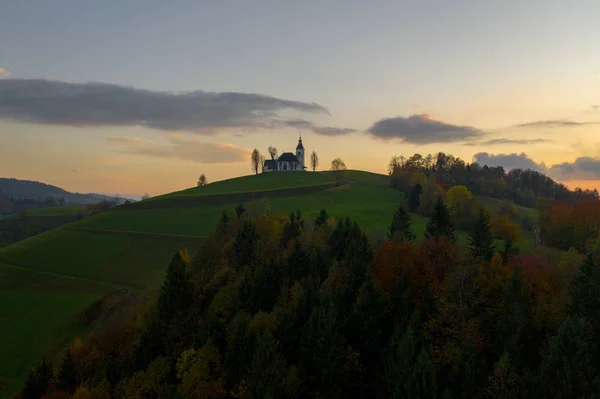 Vista aérea das colinas, floresta colorida e a igreja Sv Sobota. Eslovénia pôr do sol no outono — Fotografia de Stock