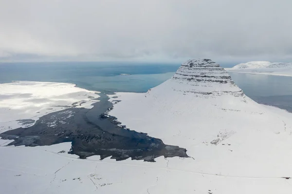 Letecký pohled na zasněženou horu Kirkjufell na začátku jara na Islandu. — Stock fotografie