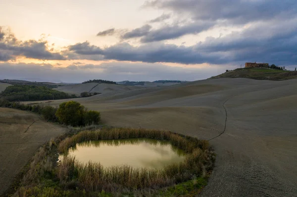 Tuscany, Siena, 20 жовтня 2019. Повітряний вид на сільський пейзаж під час заходу сонця в Тоскані. Сільська ферма, кипарисові дерева, зелені поля, сонячне світло і хмари. Італія, Європа. — стокове фото