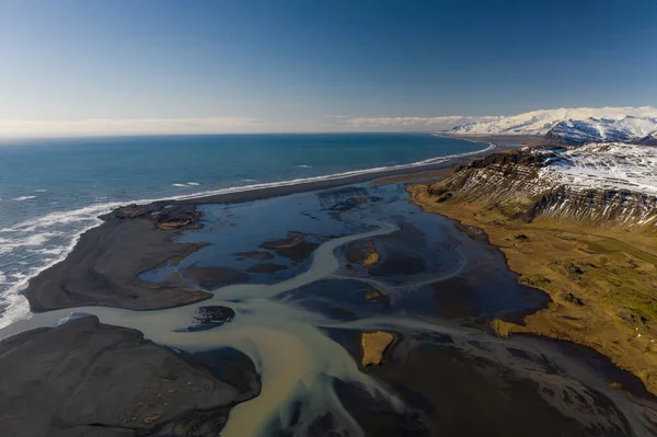 海に流れるアイスランドの川のパターンの空中ビュー。早春のアイスランド — ストック写真