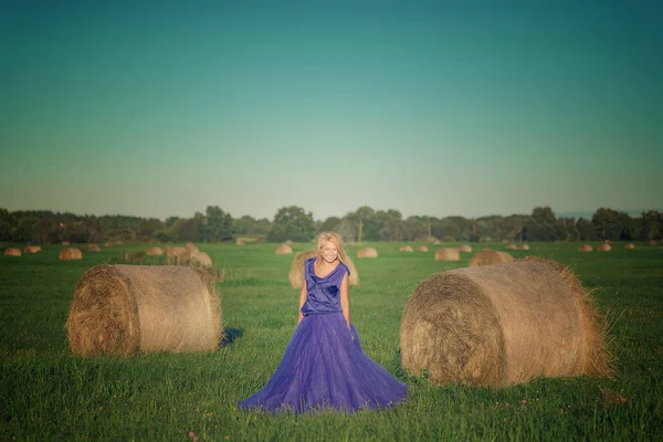 Mulher sexy na pilha de feno no pôr do sol . — Fotografia de Stock