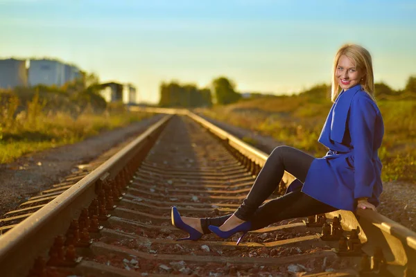 Mulher loira em casaco azul posando em railraod — Fotografia de Stock