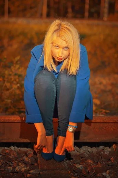 Mulher loira em casaco azul posando em railraod — Fotografia de Stock