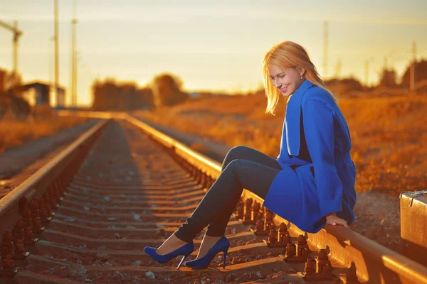 Femme blonde en manteau bleu posant sur rail — Photo