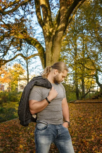 Dlouhosrsté muž pózuje v podzimní park — Stock fotografie