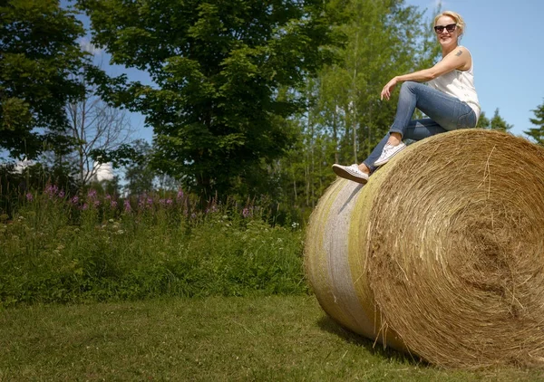 Beautiful woman sitting on a haystack — Stock Photo, Image