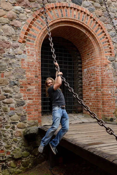 Longhair man hang on a big chain in Trakai Castle — Stock Photo, Image